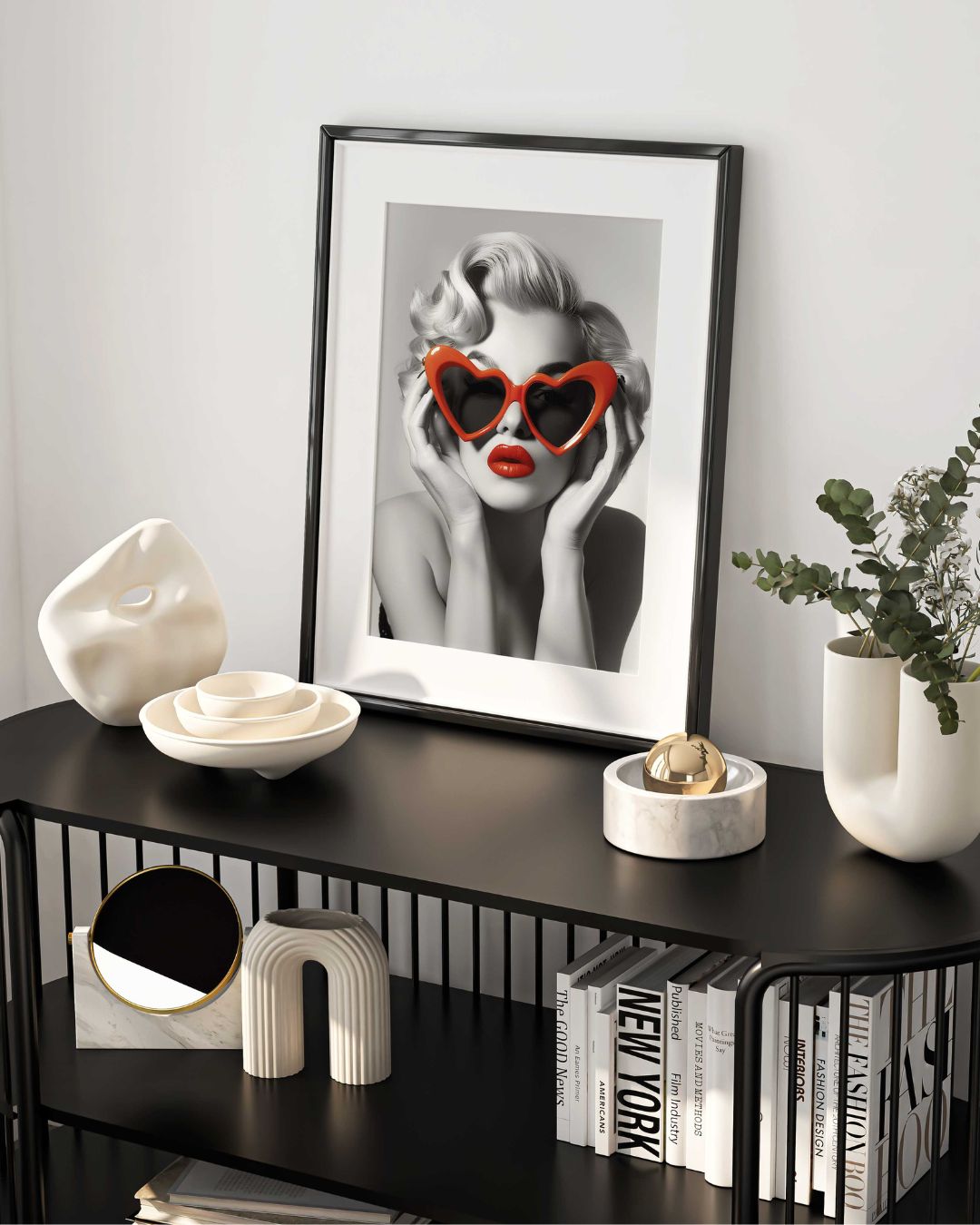 affiche d'art de Marilyn Monroe en noir et blanc portant des lunettes plastique rouge en forme de coeur, affiche mise en situation dans un cadre noir sur un buffet design